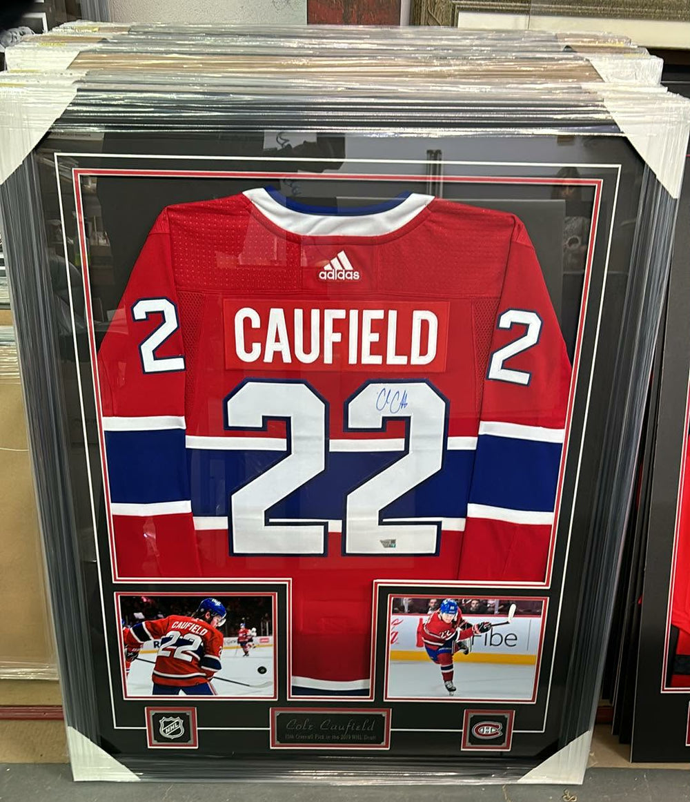 Framed montreal canadiens jersey with number 22 and name 'Caufield' on a shelf.